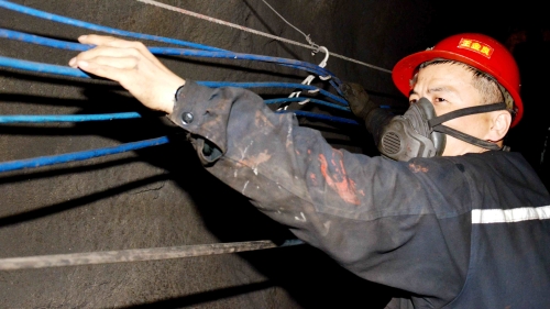 圖為新興礦提運區維修段職工王金良正在整理巷道光纜，確保安全生產。_副本